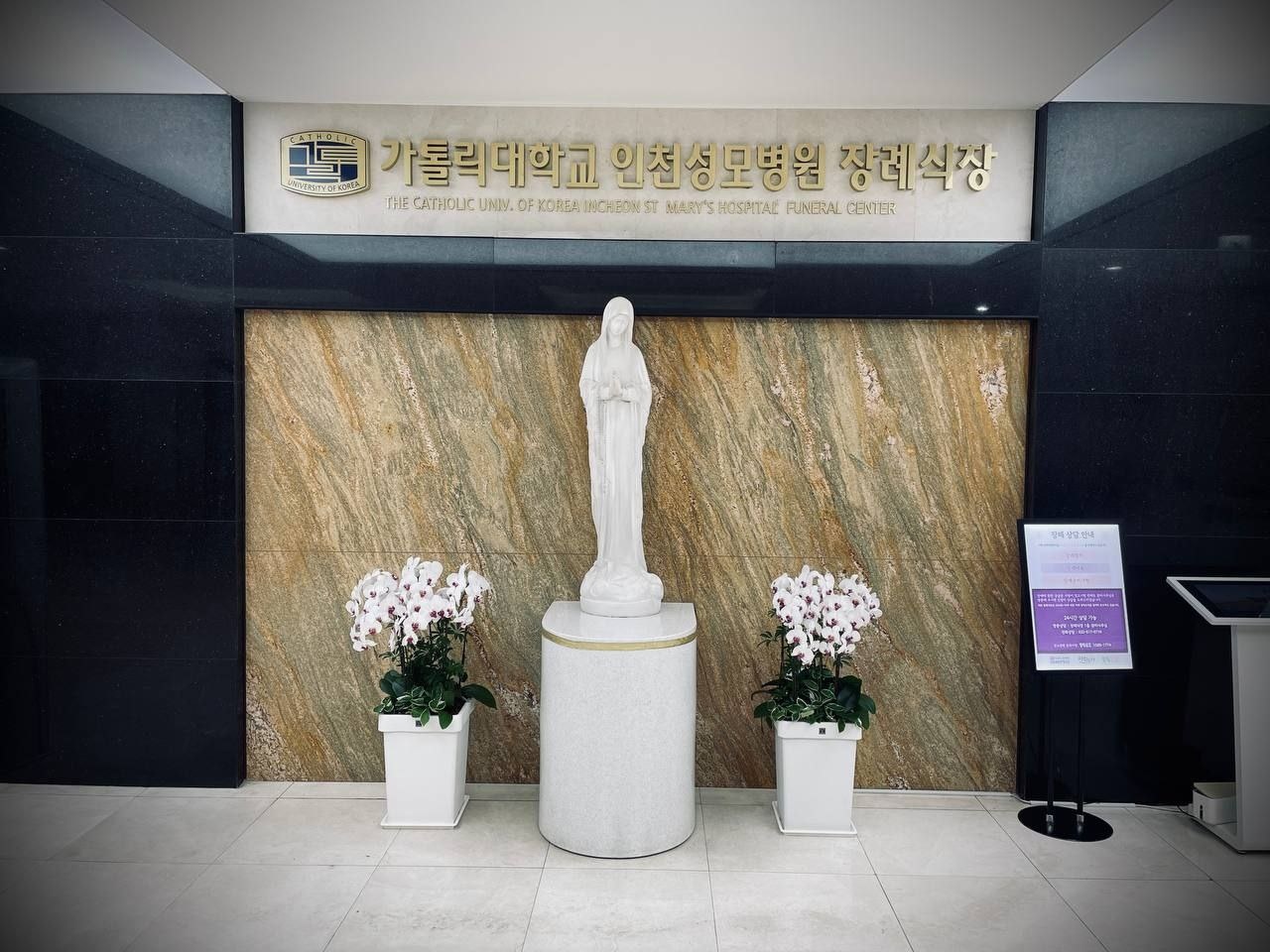 인천성모장례식장 성모상과 금색 현판 성모상과 금색 현판이 보이는 장례식장 로비